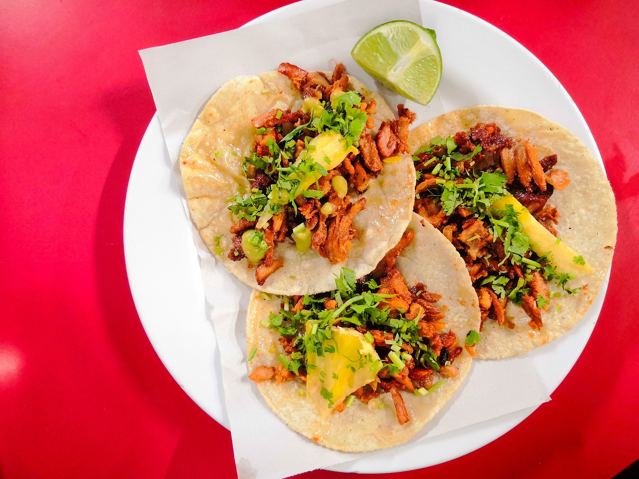 Plate with 3 tacos and a red background